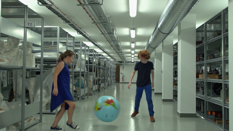 Matthias Dubreuil et Agathe van Kempen jouant avec un globe terrestre dans les réserves du matériel scientifique et didactique du Musée national de l'éducation (Munaé, Rouen). Extrait de